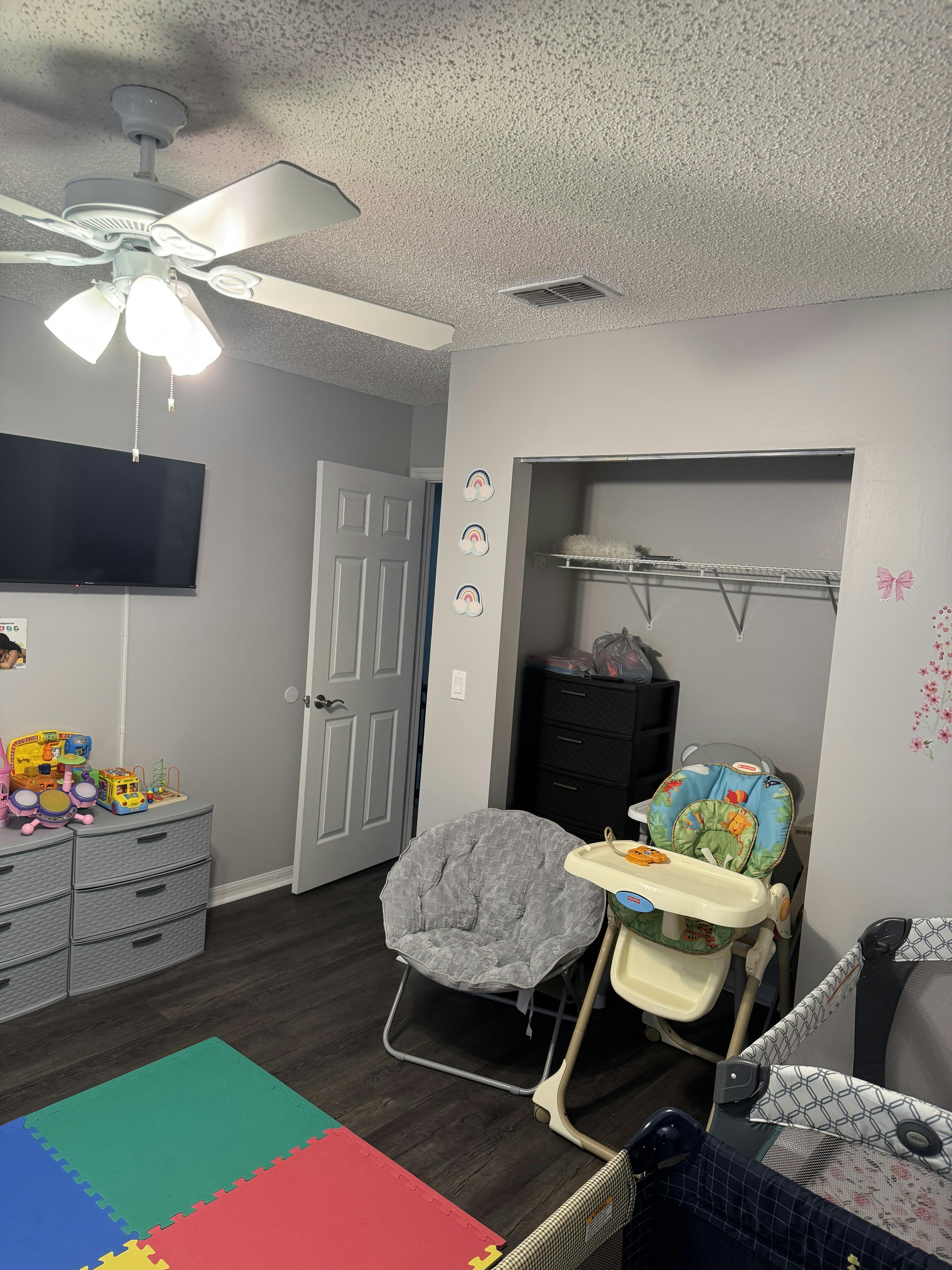 Nursery room with a crib, high chair, and play mat