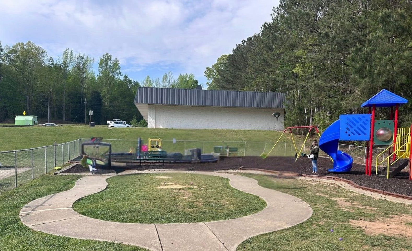 A person standing by a swing set on a playground
