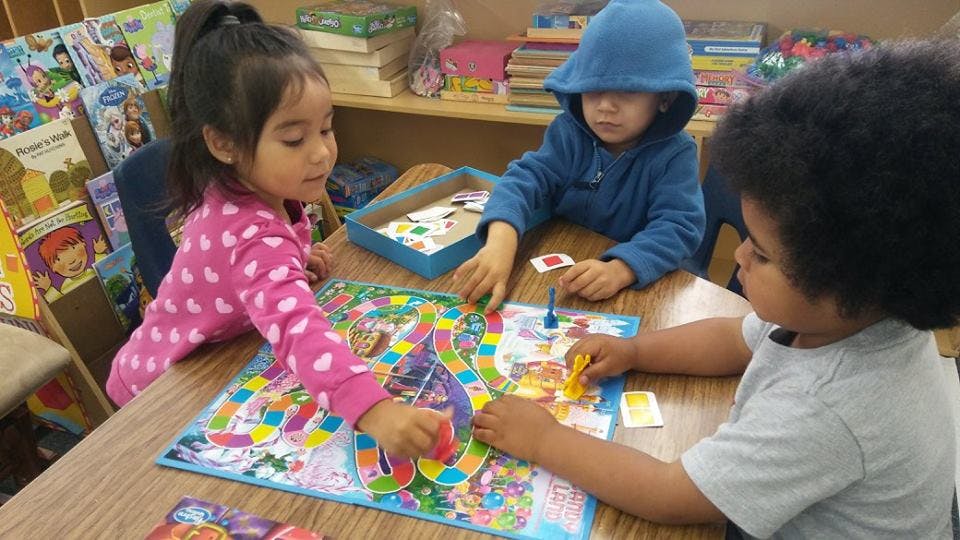 Three children playing a board game at a table