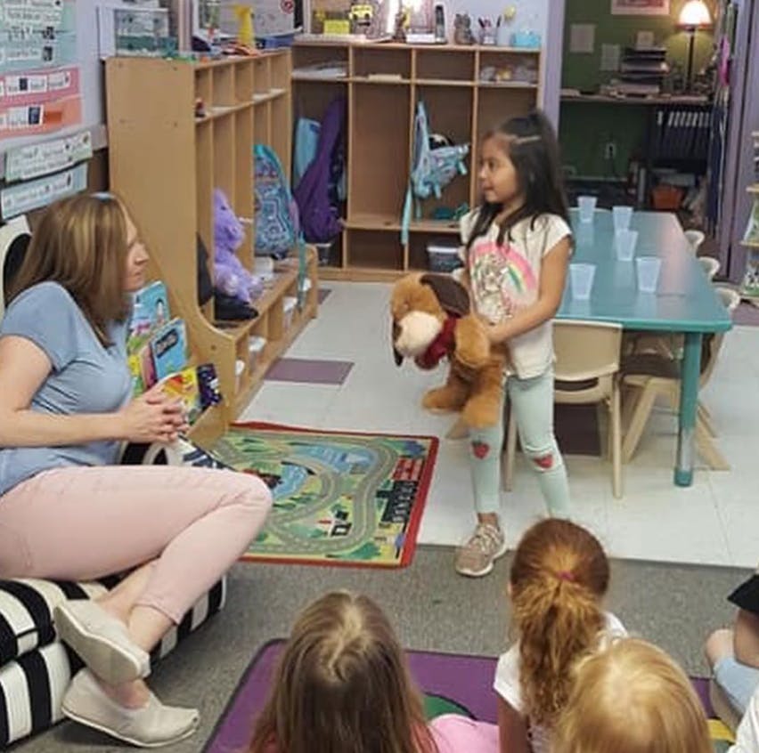 Person sitting on a couch looking at a child holding a stuffed animal