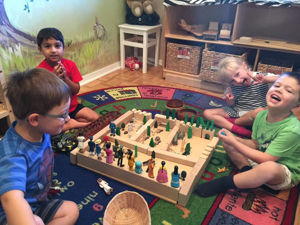 Four children playing with a wooden toy set on a colorful rug