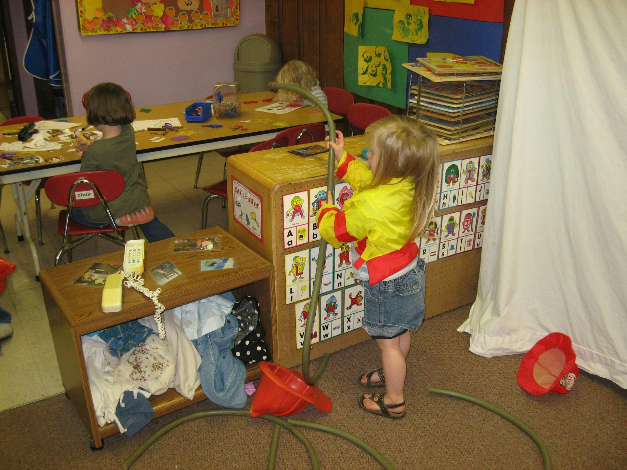 Child playing with a hose in a classroom