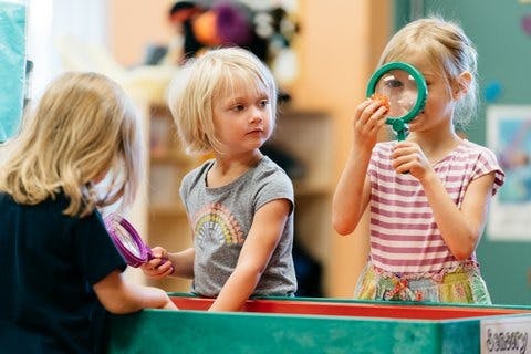 Three children playing with magnifying glasses