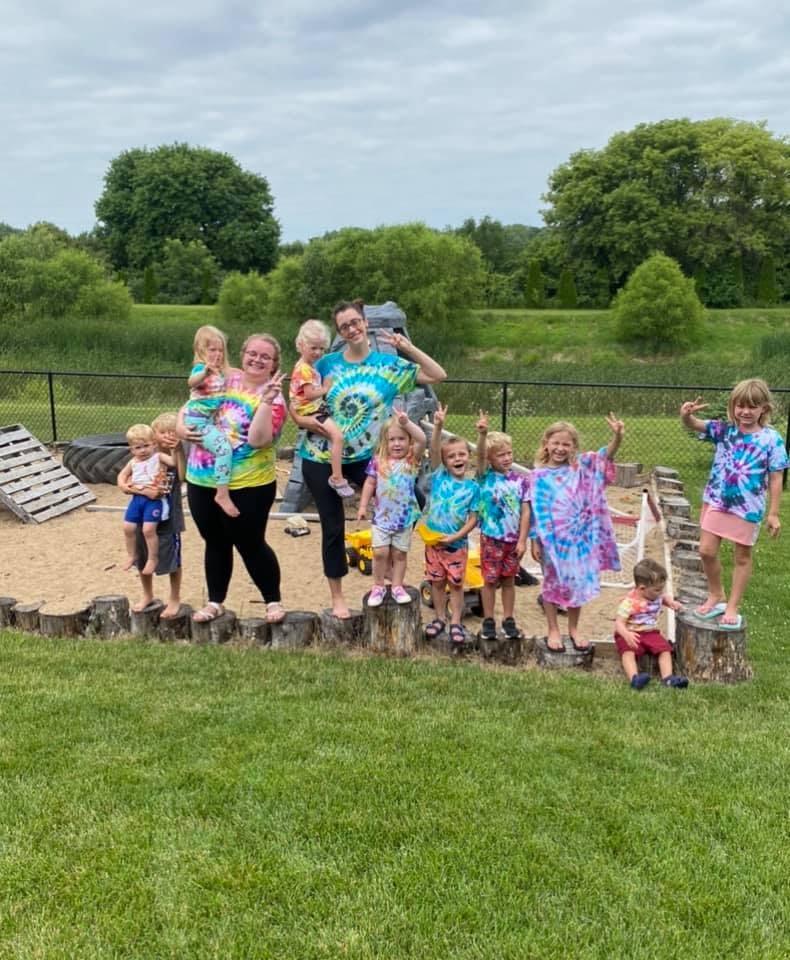 Adults and children in tie-dye shirts posing outdoors