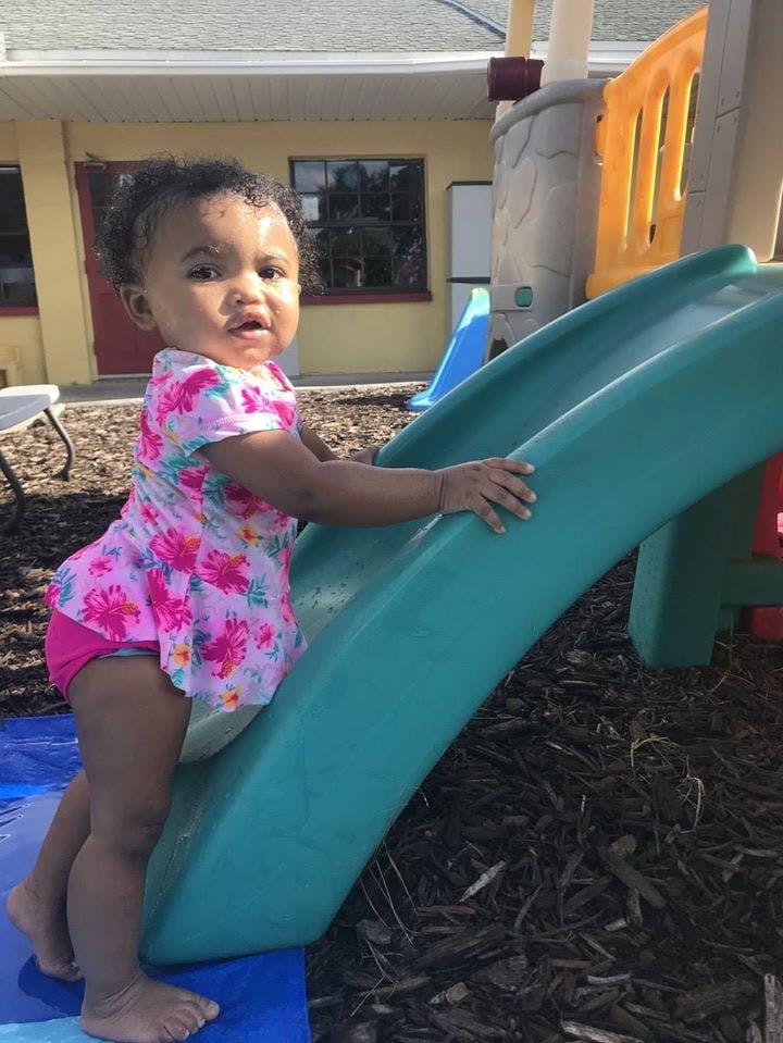 Child standing next to a slide on a playground