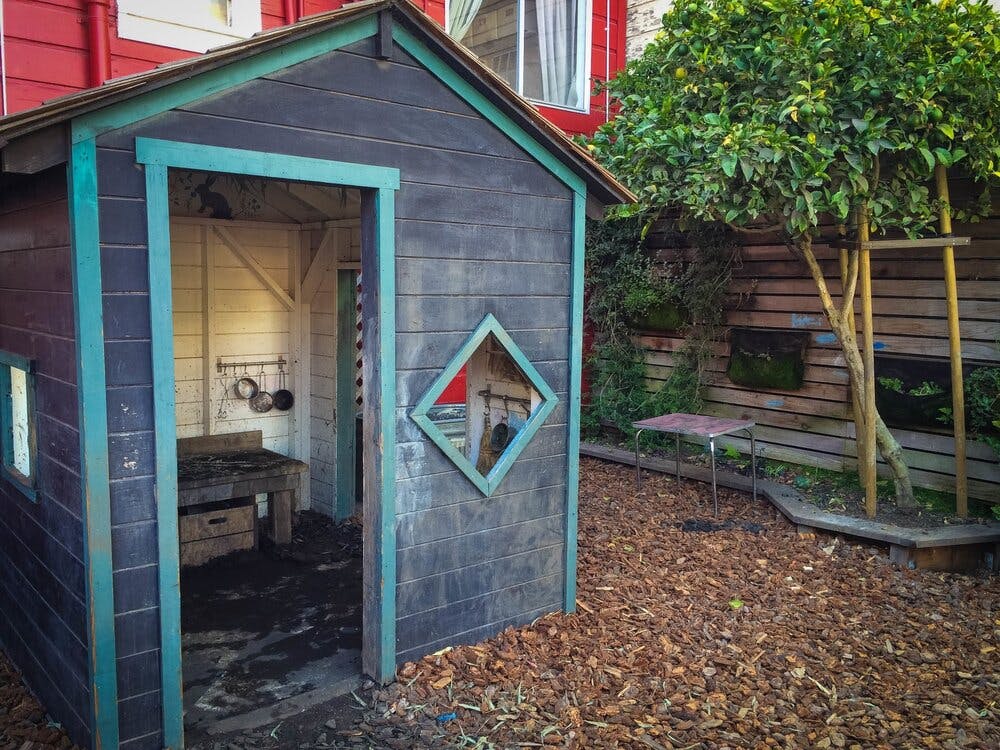 Small wooden playhouse with an open door in a yard