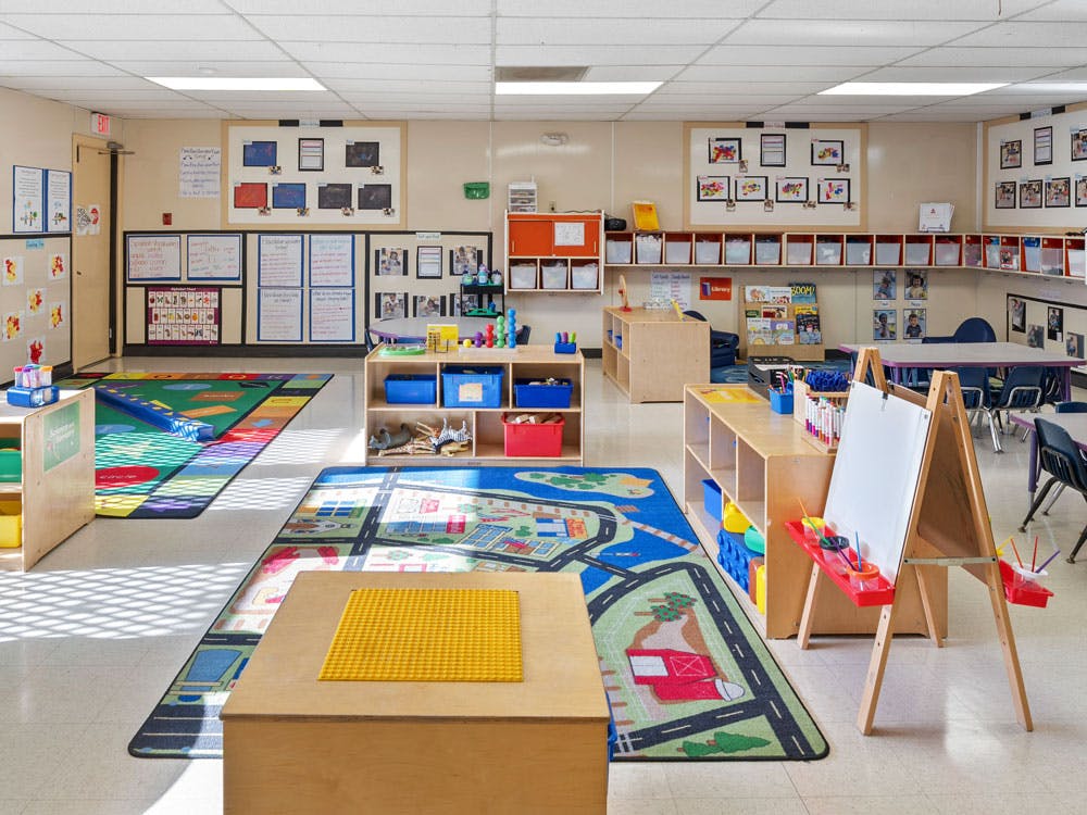 Empty colorful preschool classroom with play rugs, tables, and learning materials