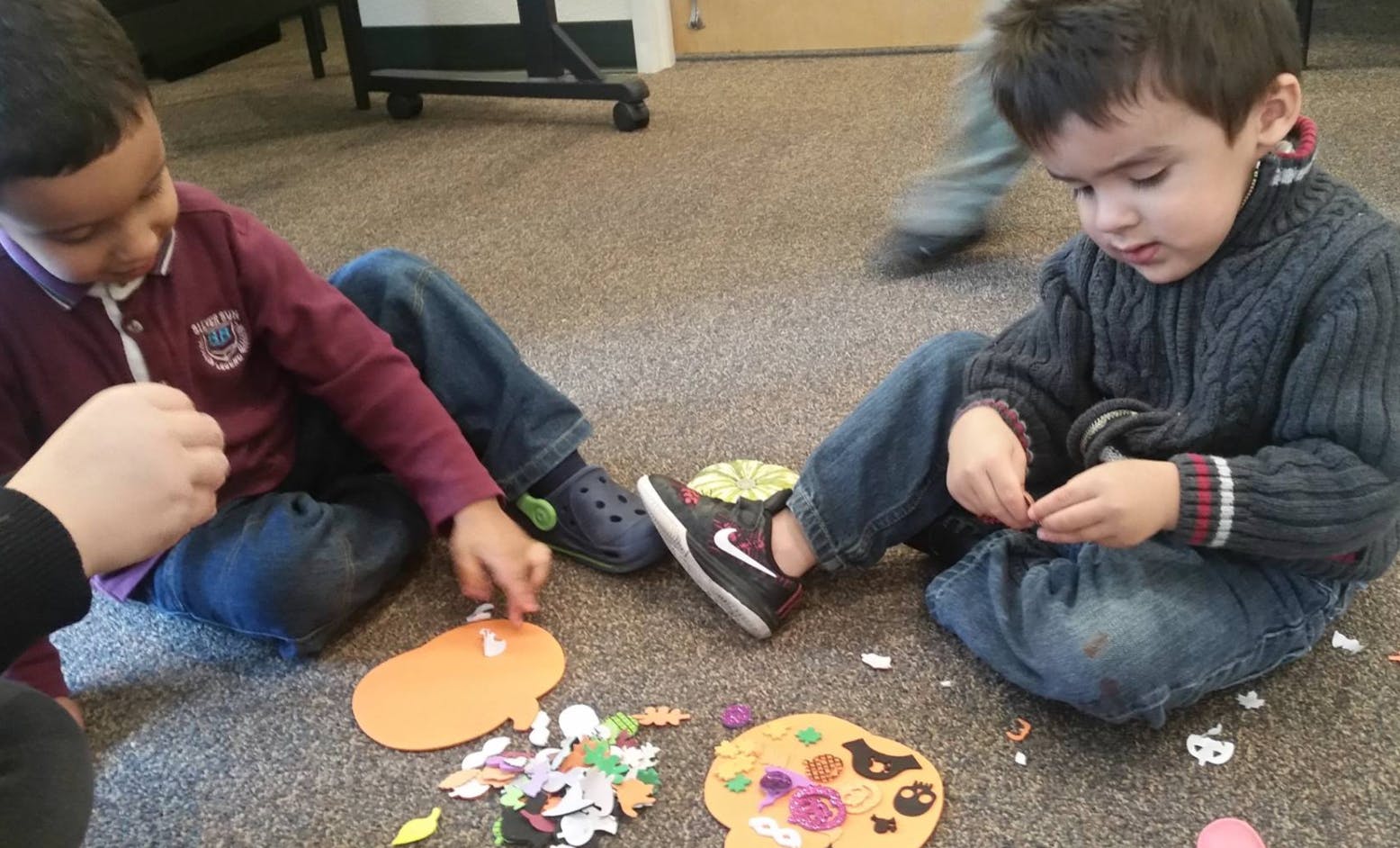 Two children sitting on the floor doing crafts