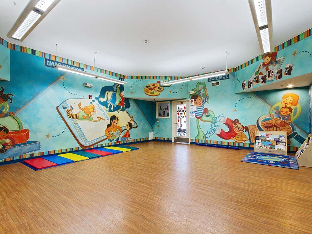 Children's classroom with bright murals and colorful mats on the floor
