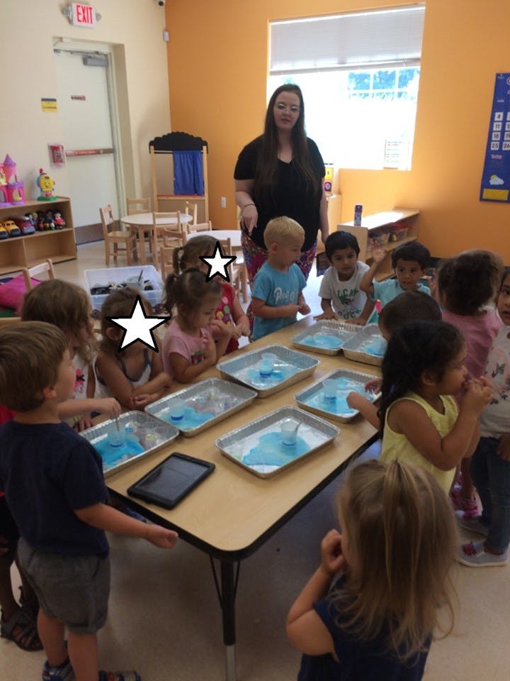 Adult and children gathered around a table with trays of blue liquid