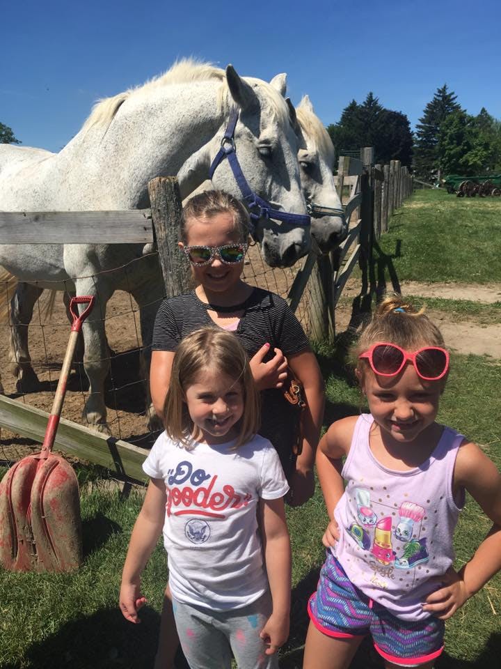 Three children standing in front of two horses