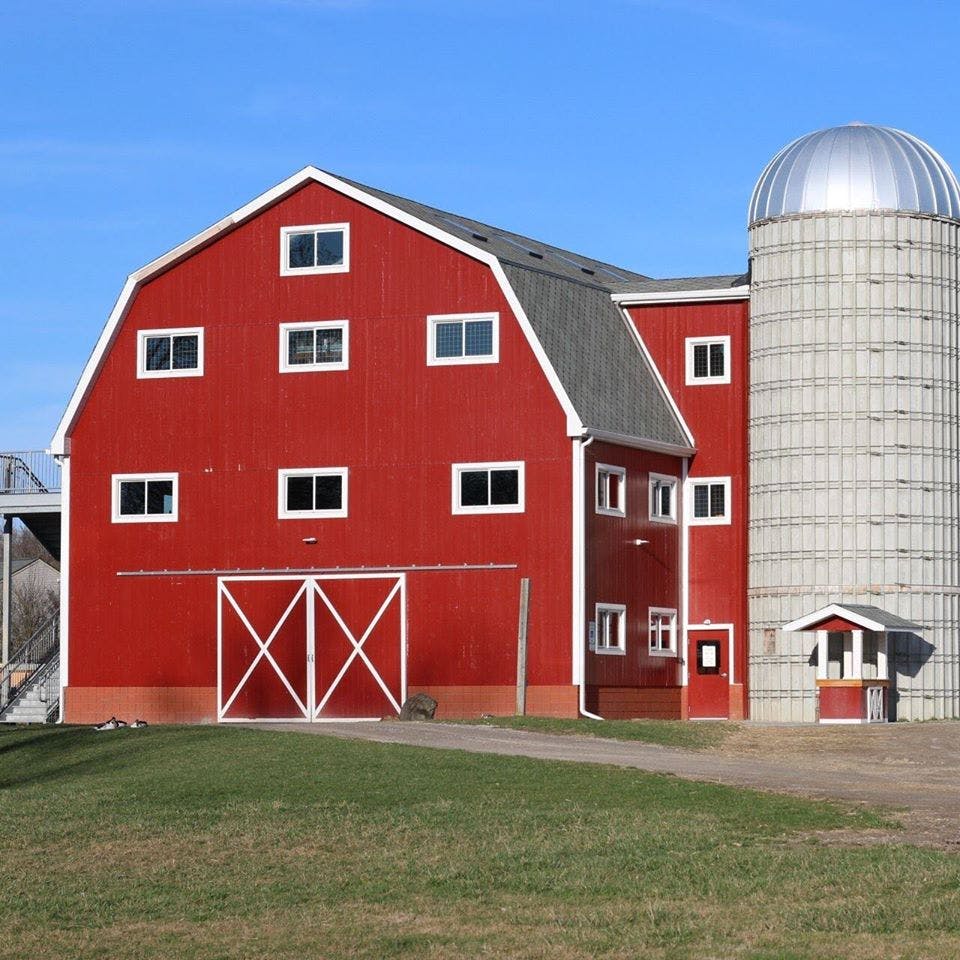 Red barn with a white trim and a silo