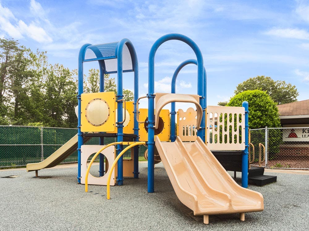 Playground with blue and yellow climbing structure and tan slides