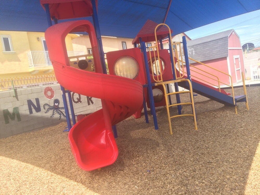 Playground with red slides and blue shade covering