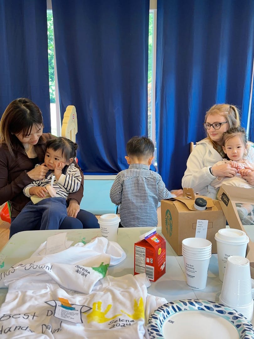 People and children at a table with white t-shirts and cups