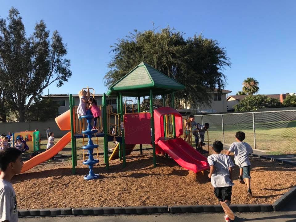 Children playing on a playground structure with slides and climbing structures
