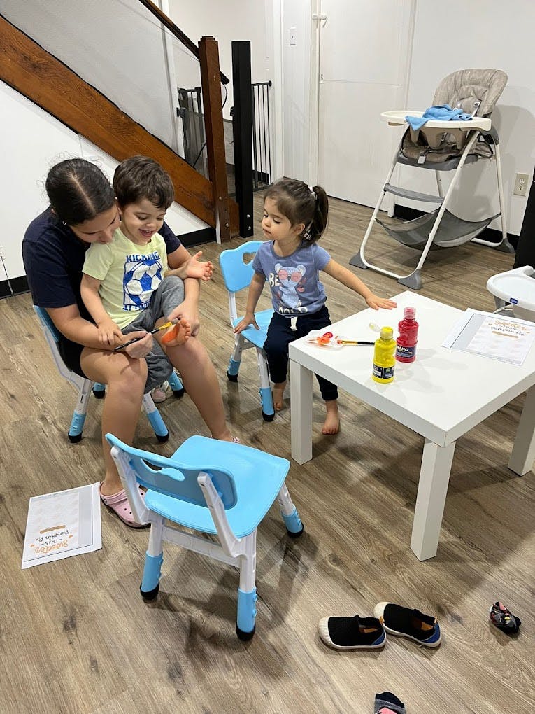 Person and two children sitting at a table with art supplies