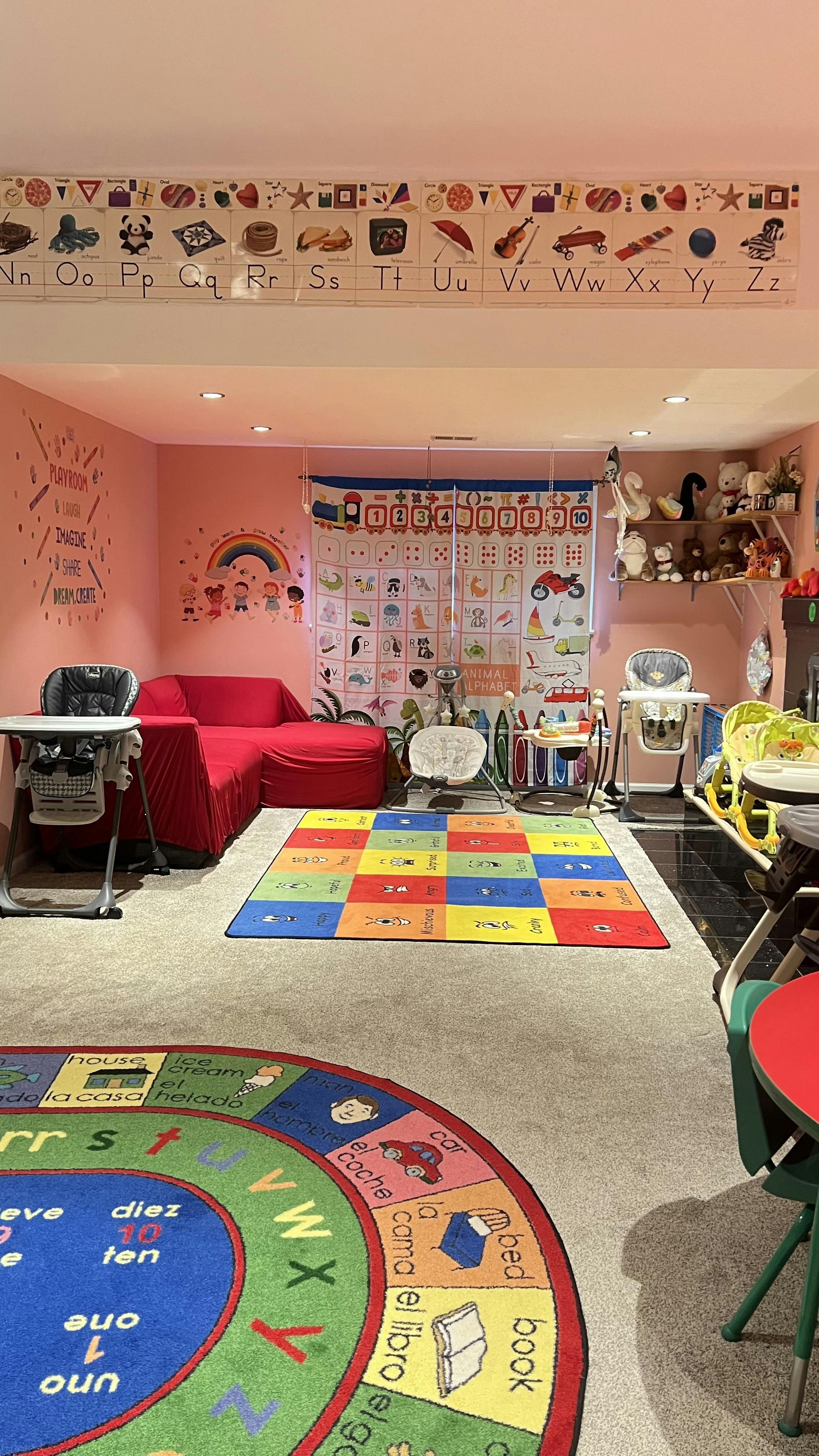 Playroom with alphabet border, red sofa, and colorful rugs