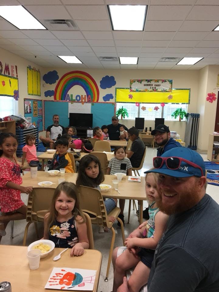 People and children sitting at tables in a classroom