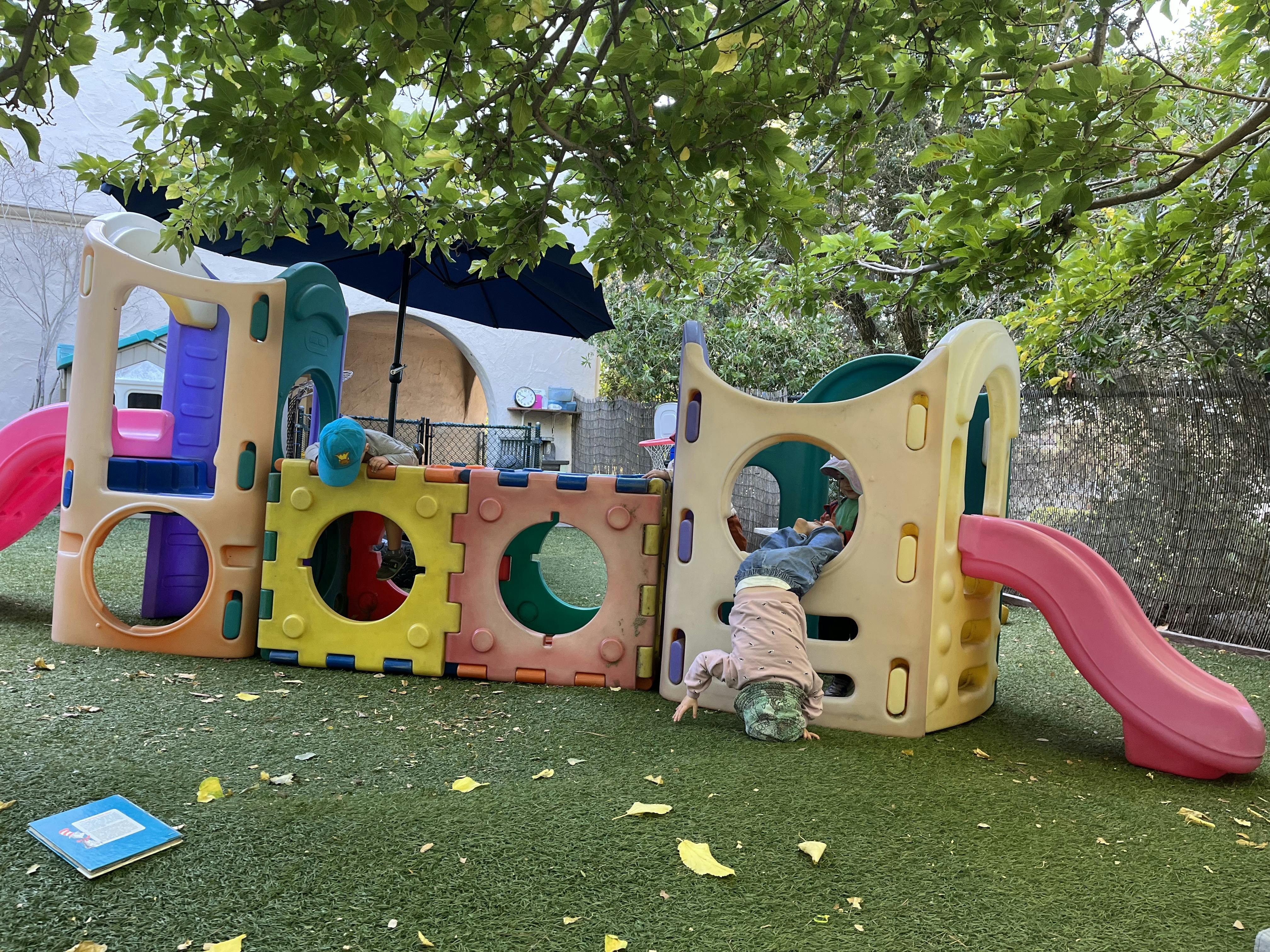 Child hanging upside down from a play structure next to another child