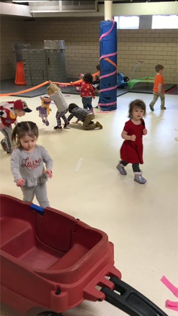 Children playing in a room with a red wagon in the foreground