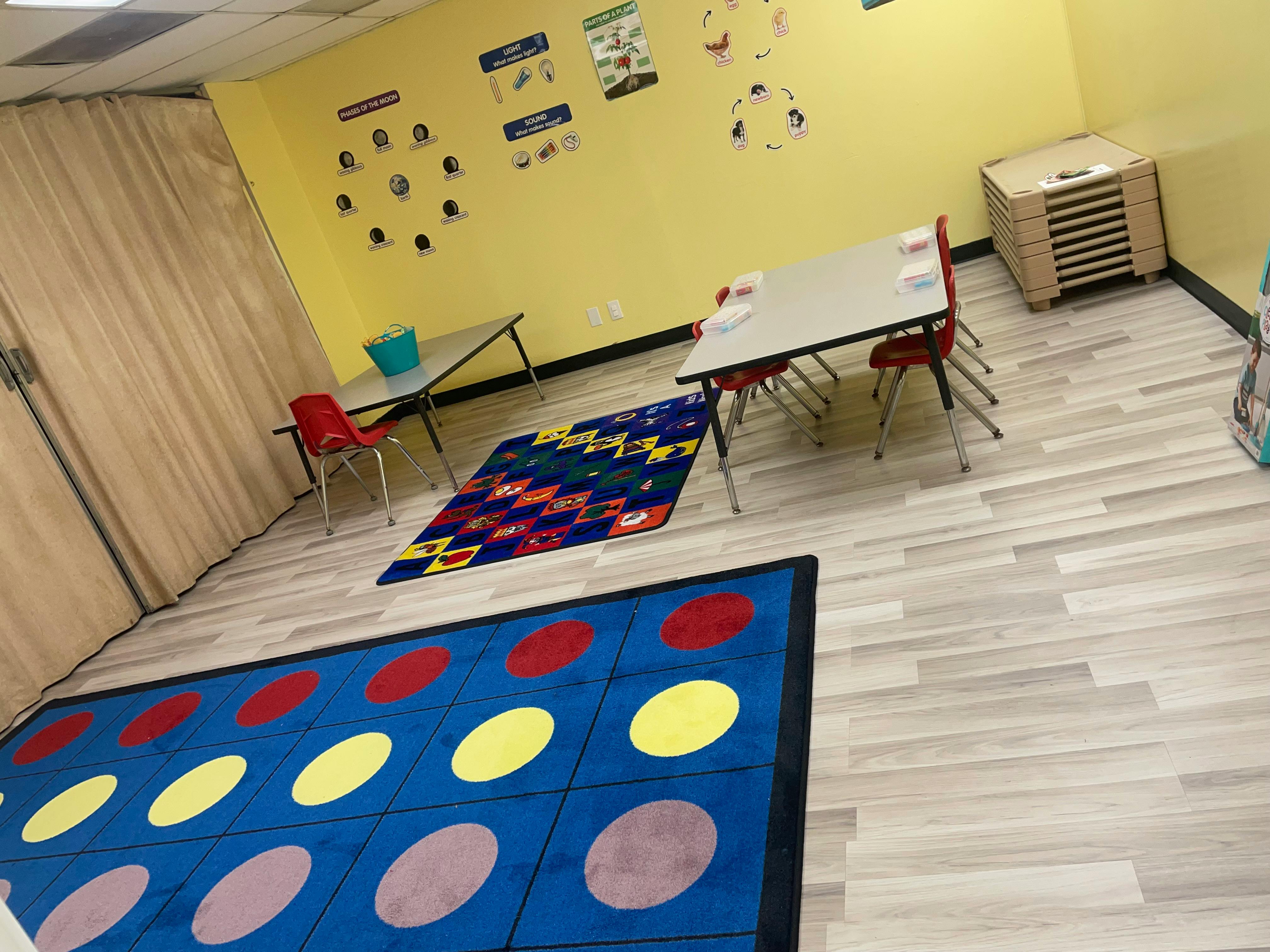 Classroom with tables, chairs, and colorful rugs