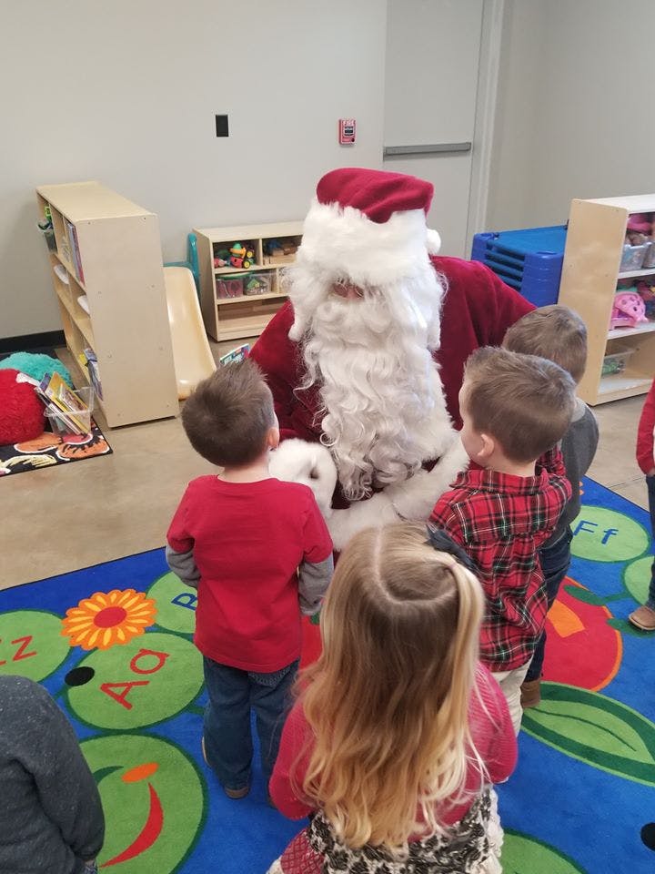 Person dressed as Santa Claus with several children gathered around