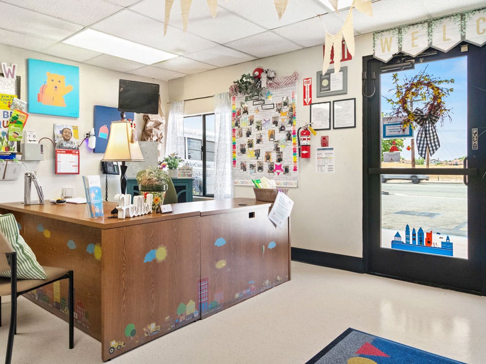 Reception desk decorated with child-like drawings in a brightly lit room