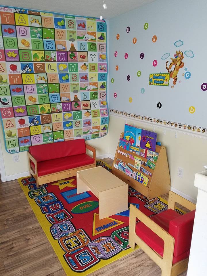 Children's play area with a red couch, small table, and bookshelf