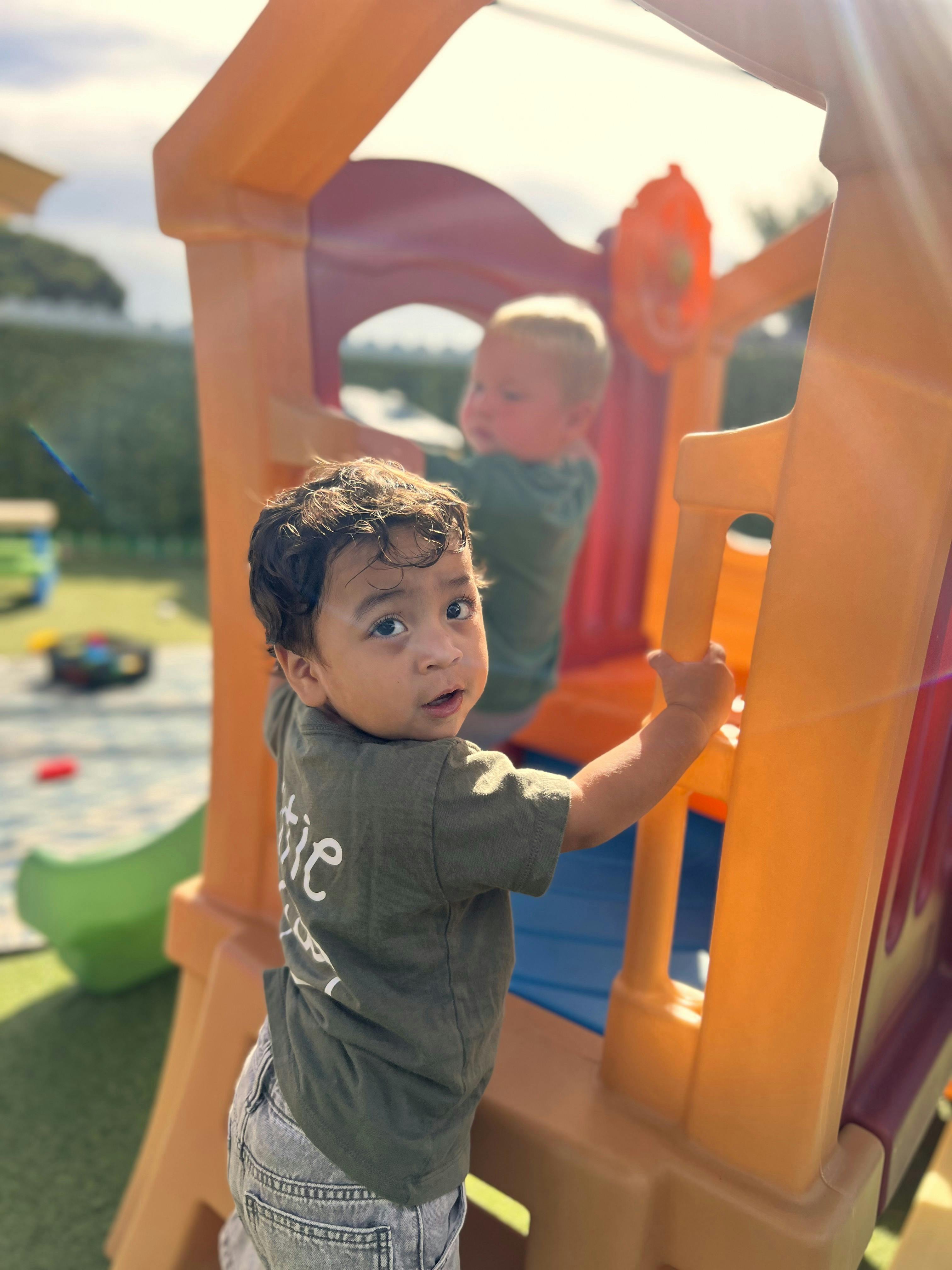 Two children playing on a plastic outdoor play structure