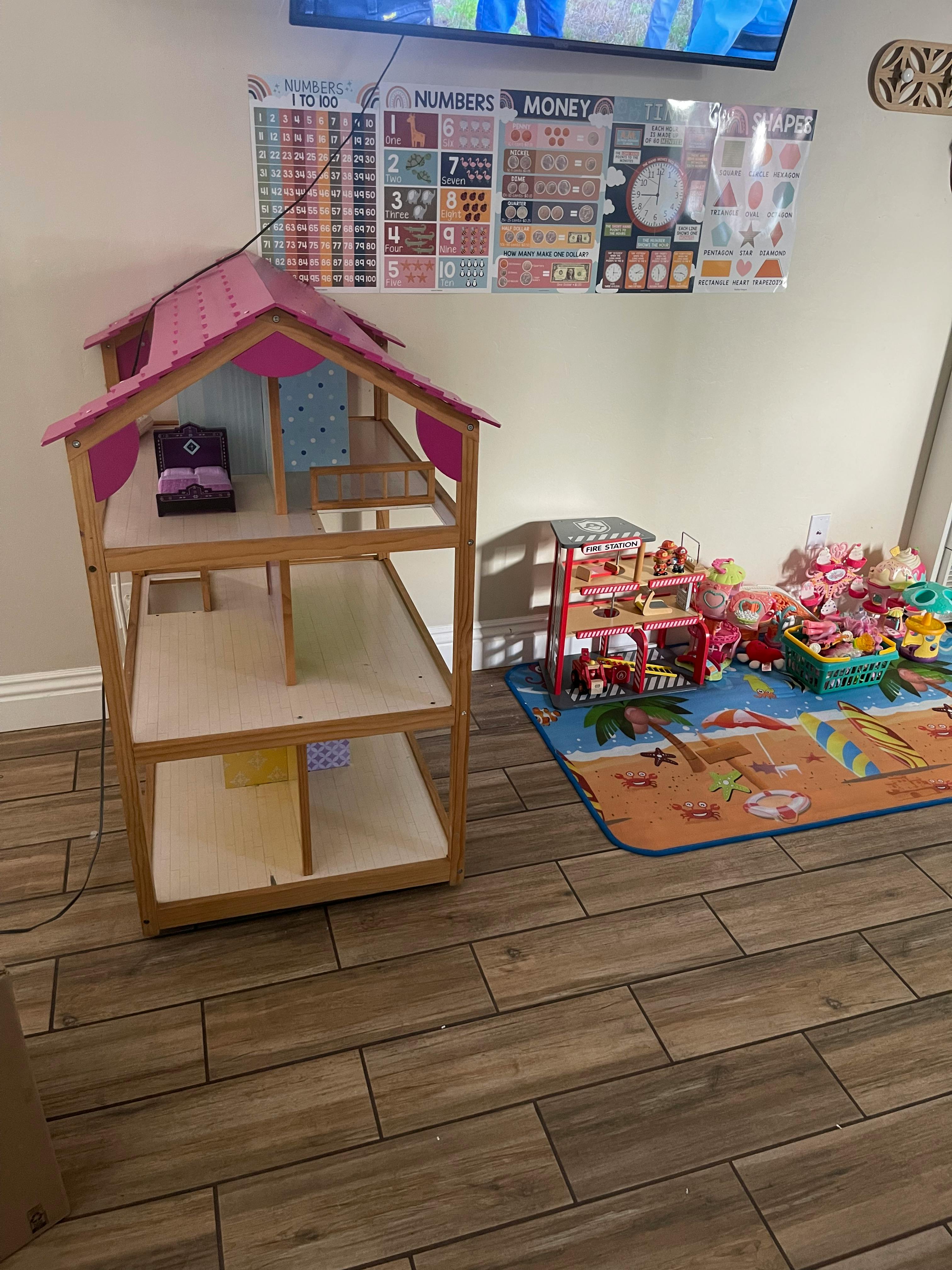 Dollhouse with pink roof next to a play mat with toys