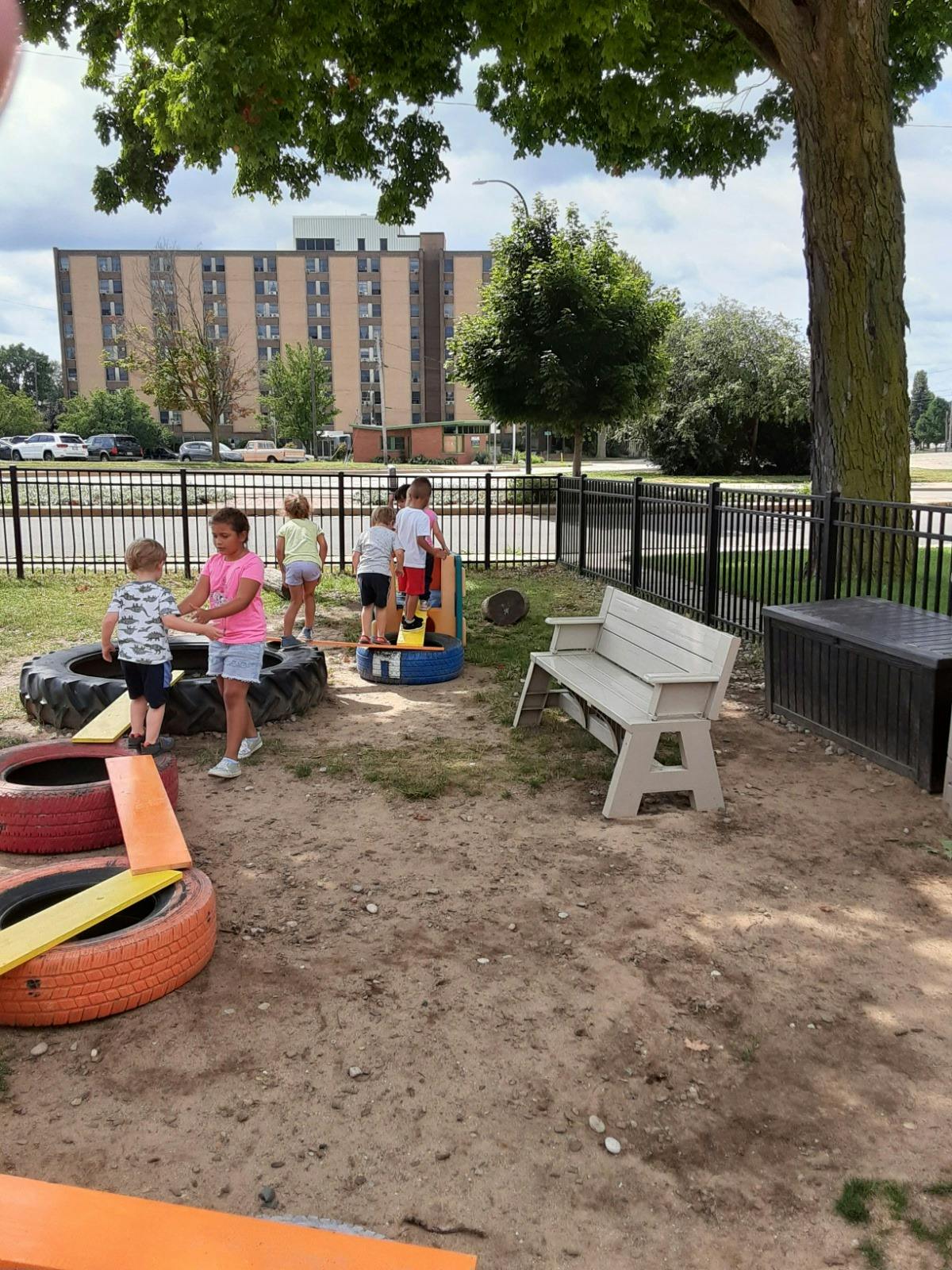 Children playing on tires and a small structure outdoors