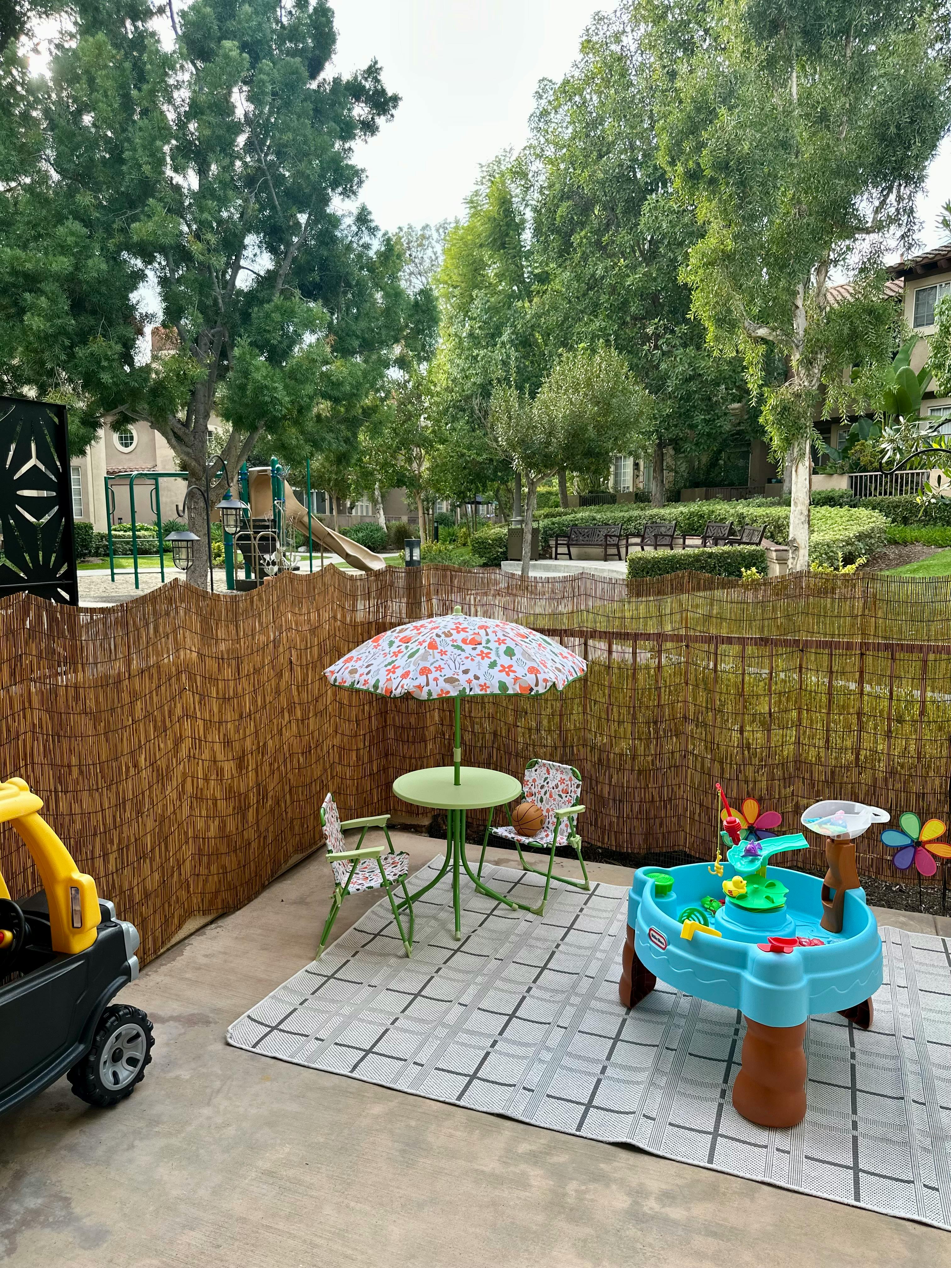 Patio with children's table and umbrella, water play table, and toy car
