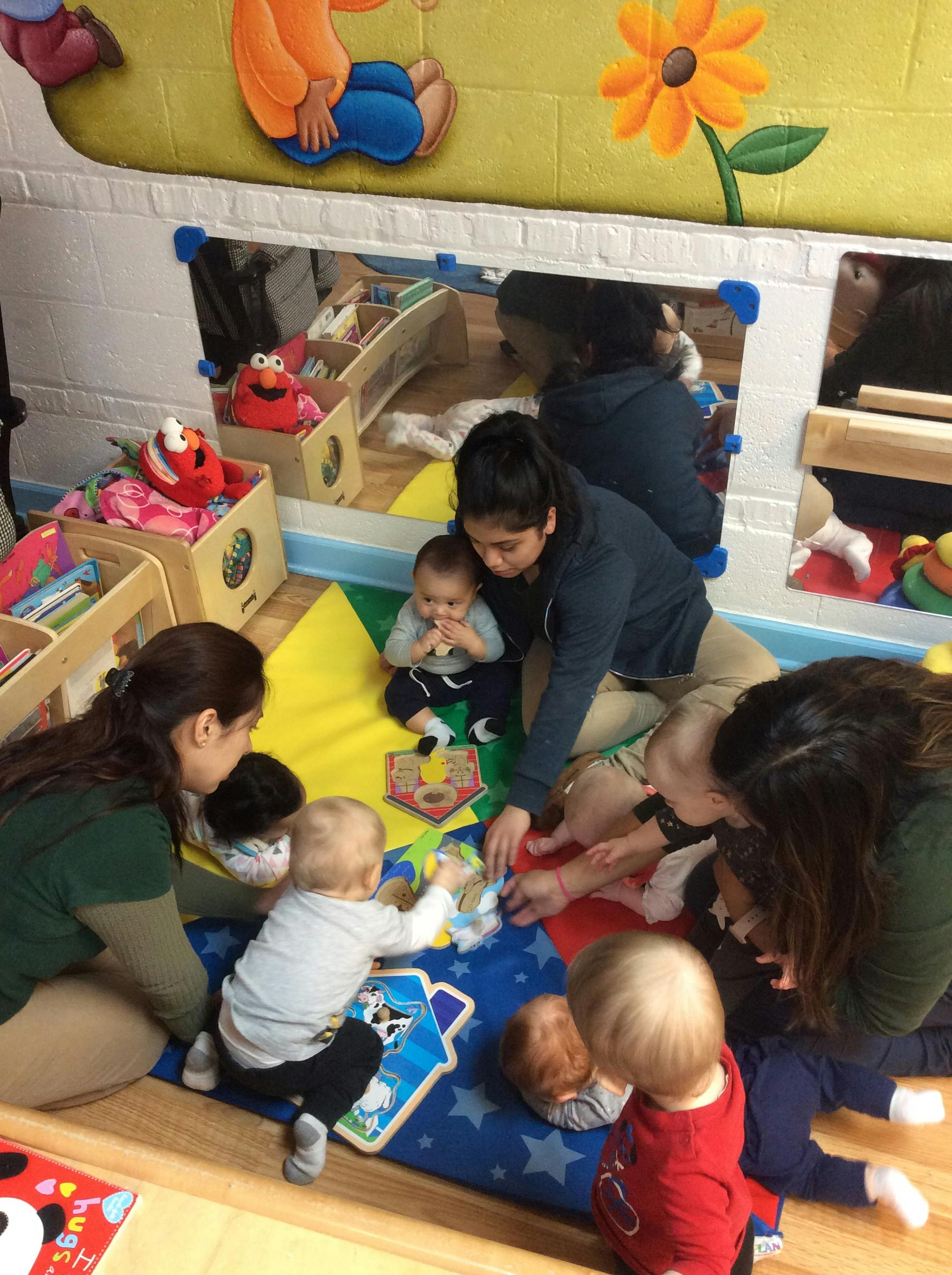 Adults and children playing with toys on a colorful mat in a room