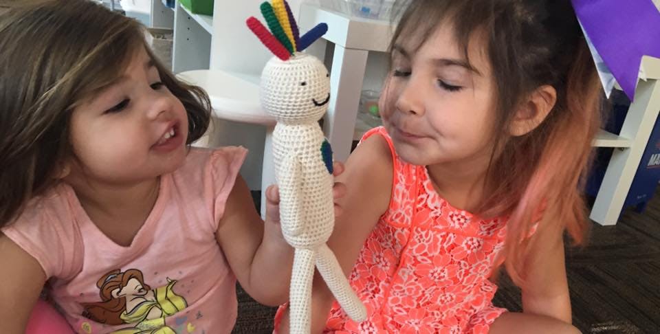 Two children looking at a crocheted doll
