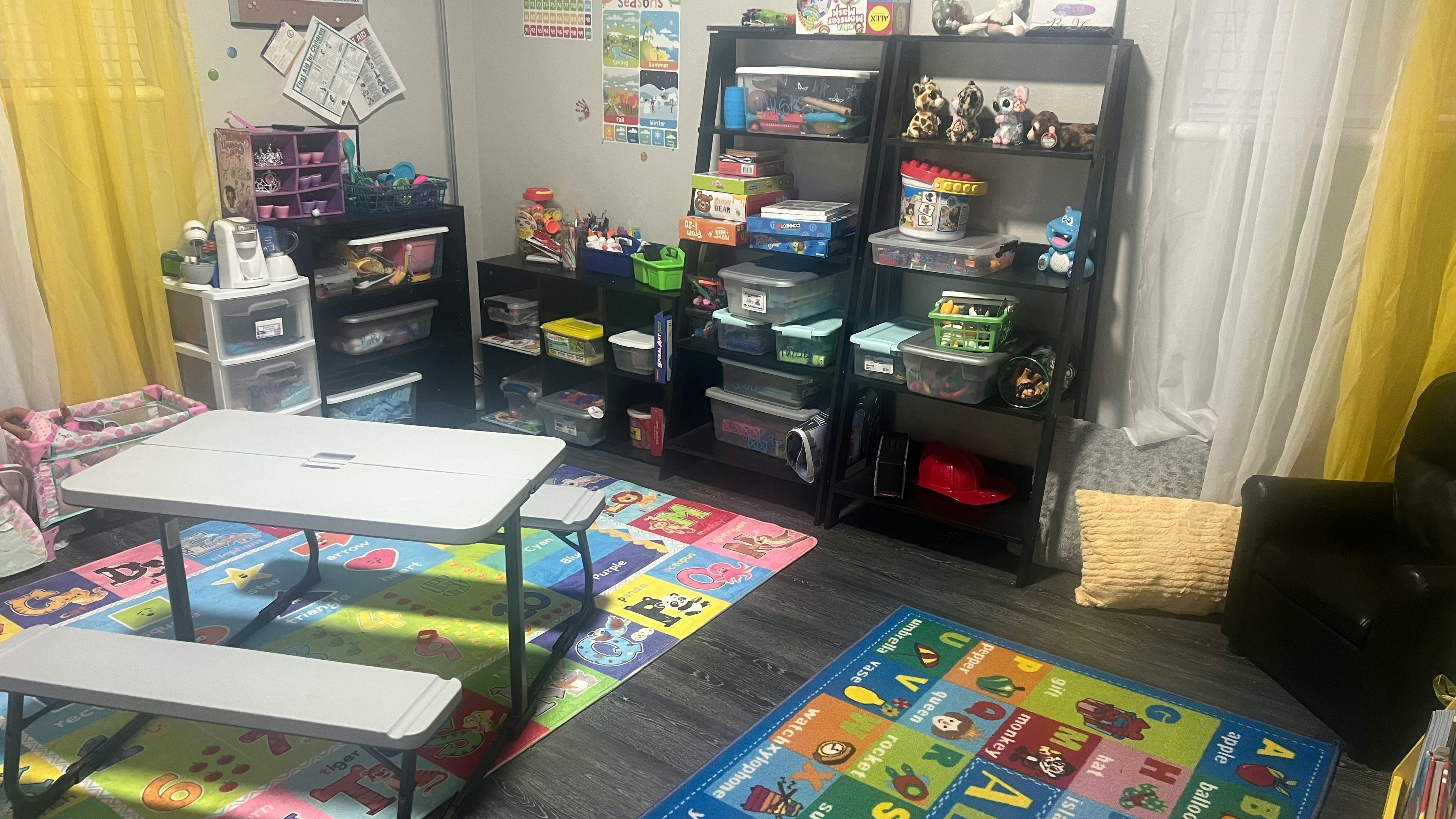 Playroom with small table and benches, shelves with toys and storage bins, storage bins