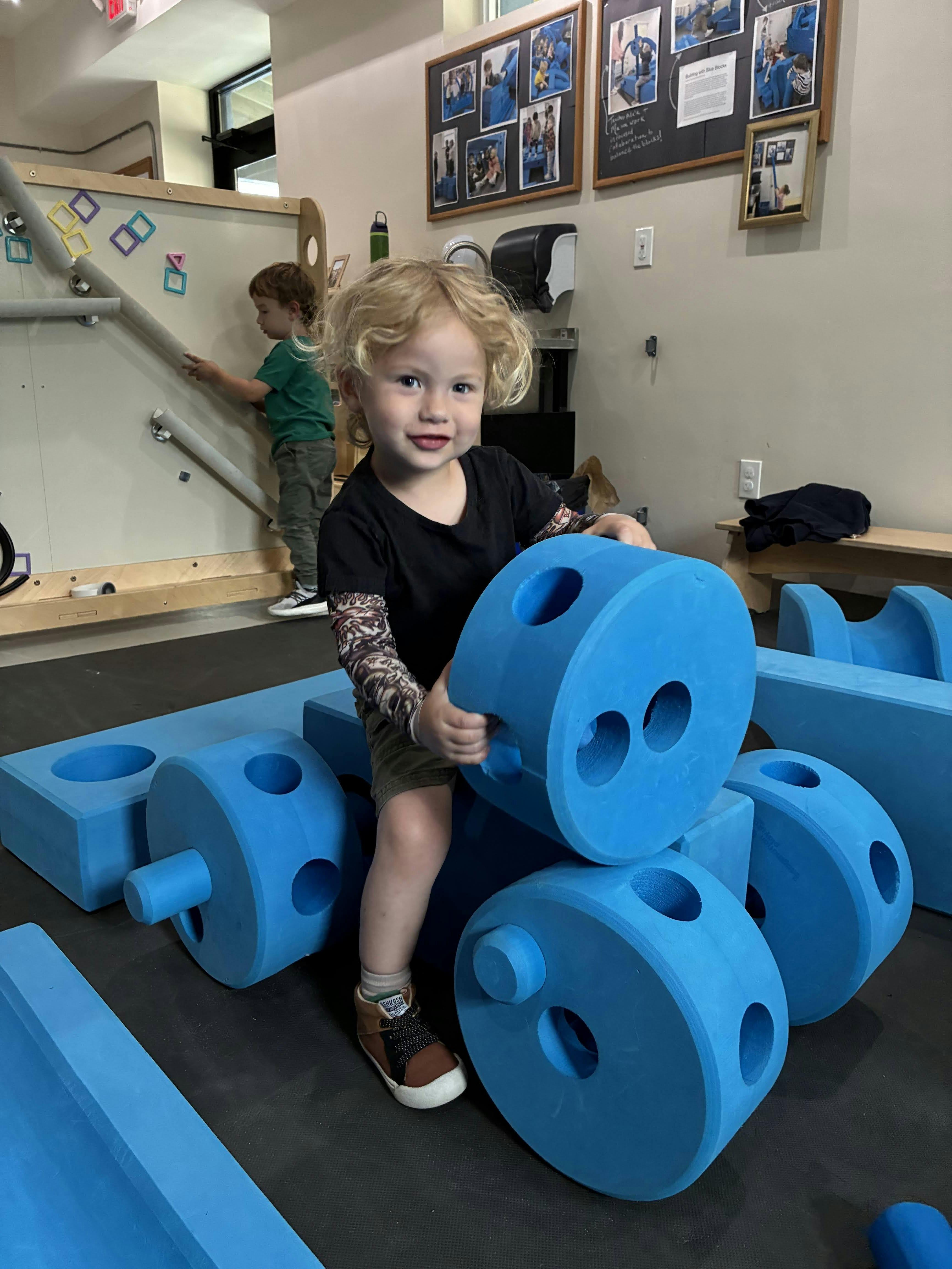 Child smiling while playing with blue foam blocks