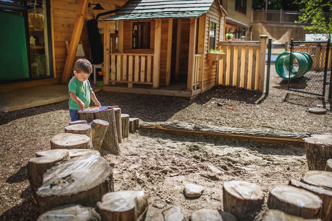 Child playing with blocks on tree stumps in a playground