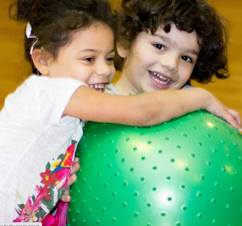 Two children behind a green exercise ball