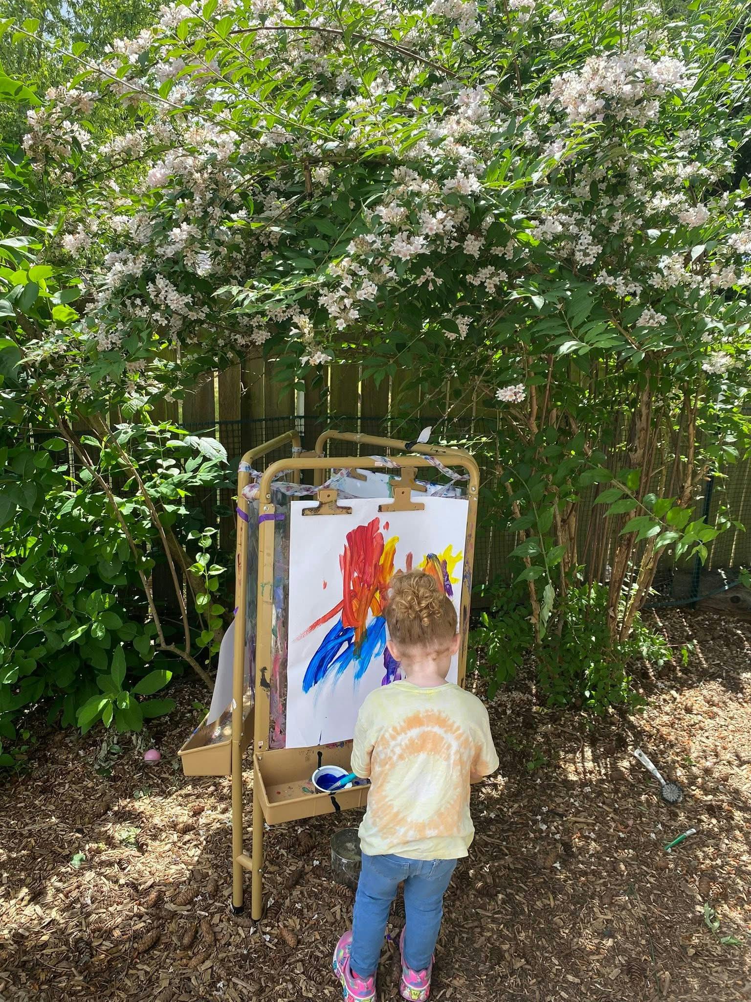 Child painting on an easel outdoors