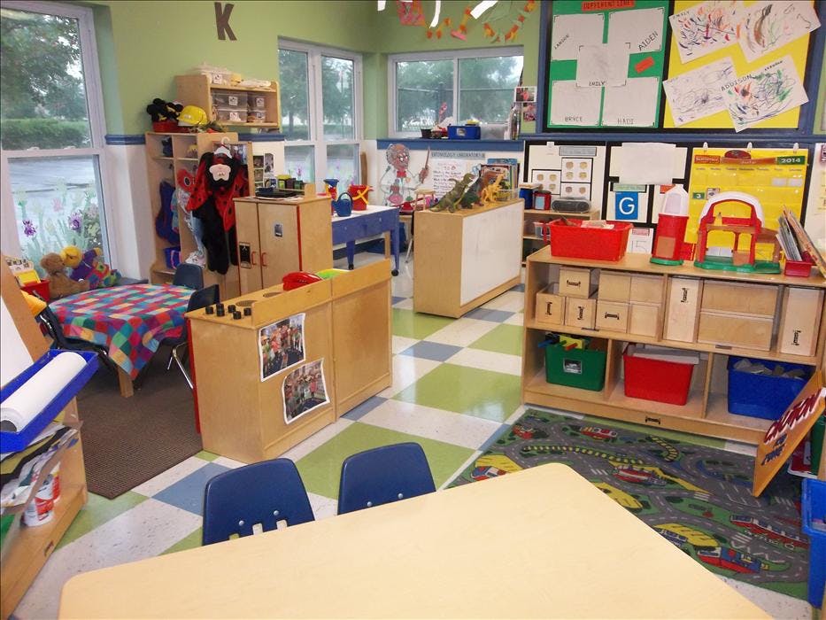 Classroom with tables, chairs, shelving units, and artwork on walls