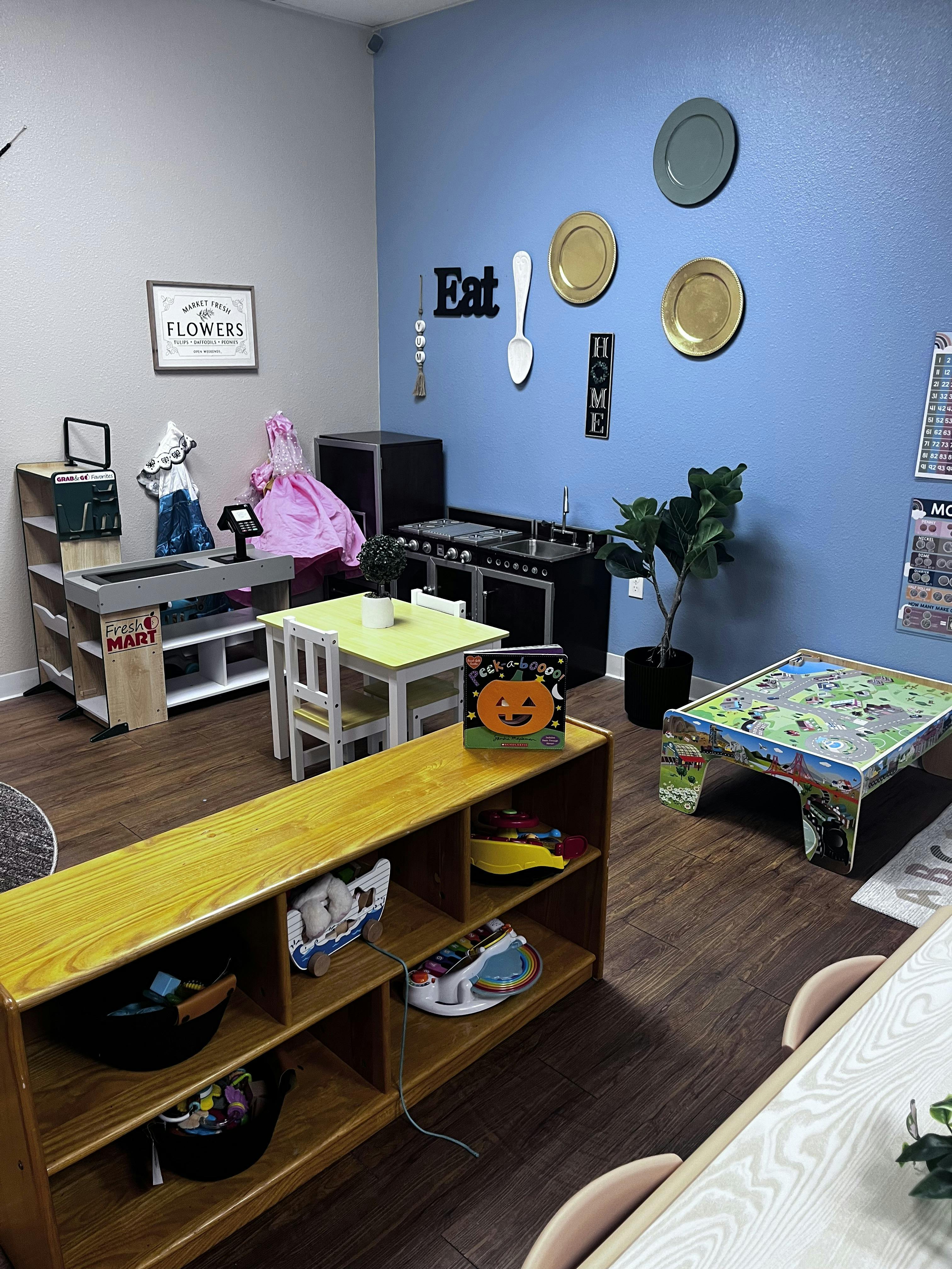 Playroom with a toy kitchen, small tables, and shelves with toys