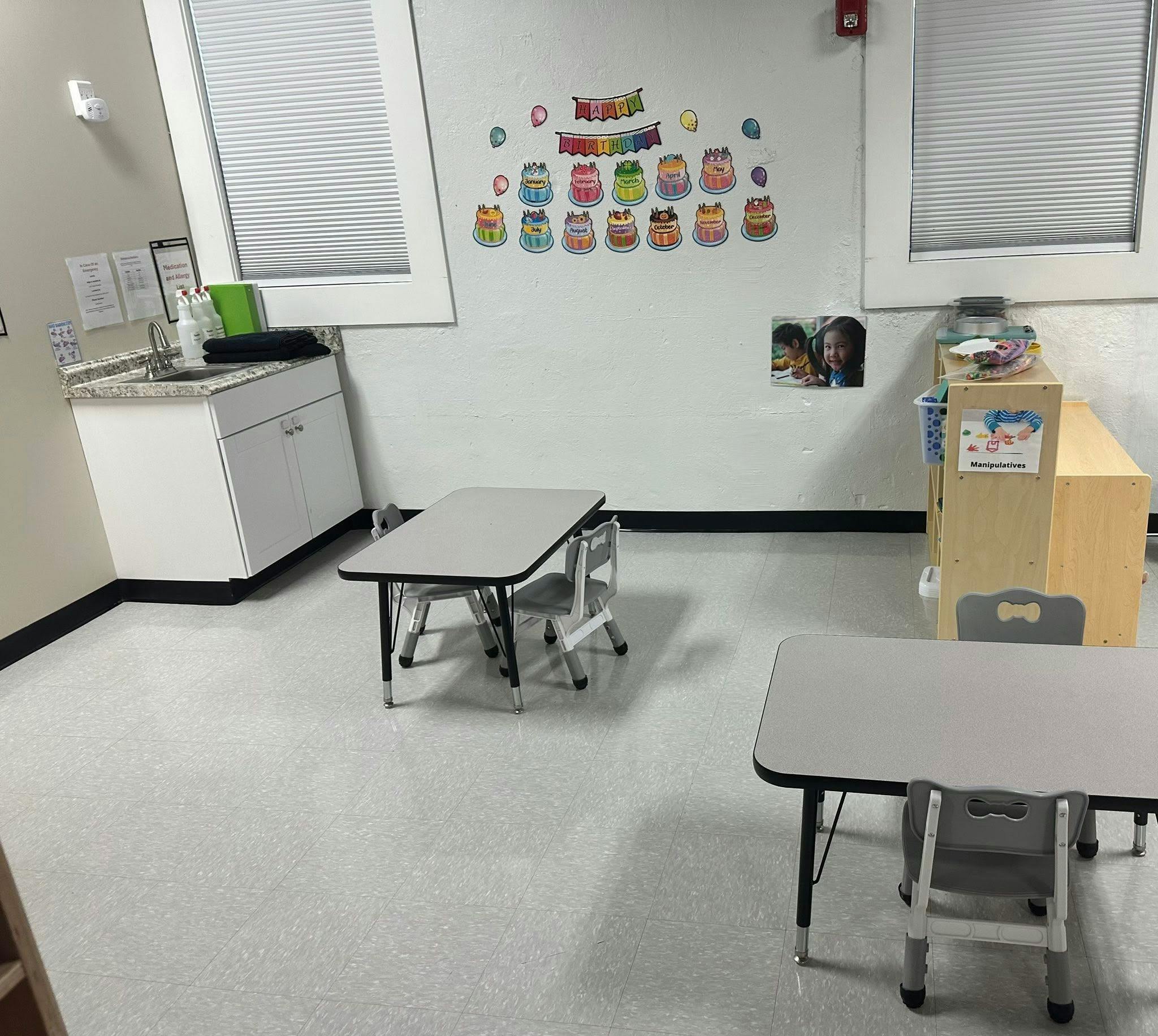 Classroom with child-sized tables and chairs, a sink, and birthday decorations