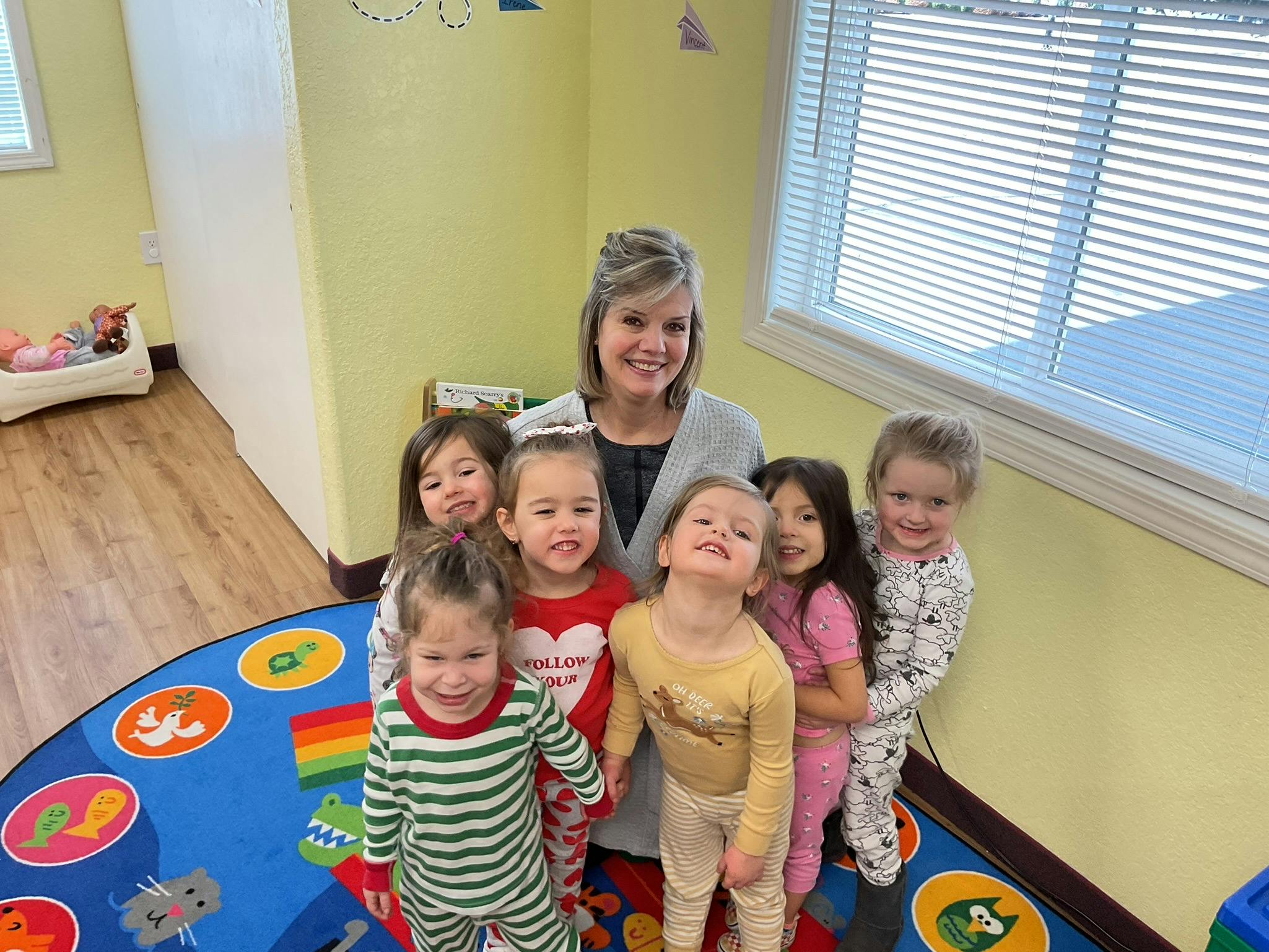 Adult and several children standing on a colorful rug