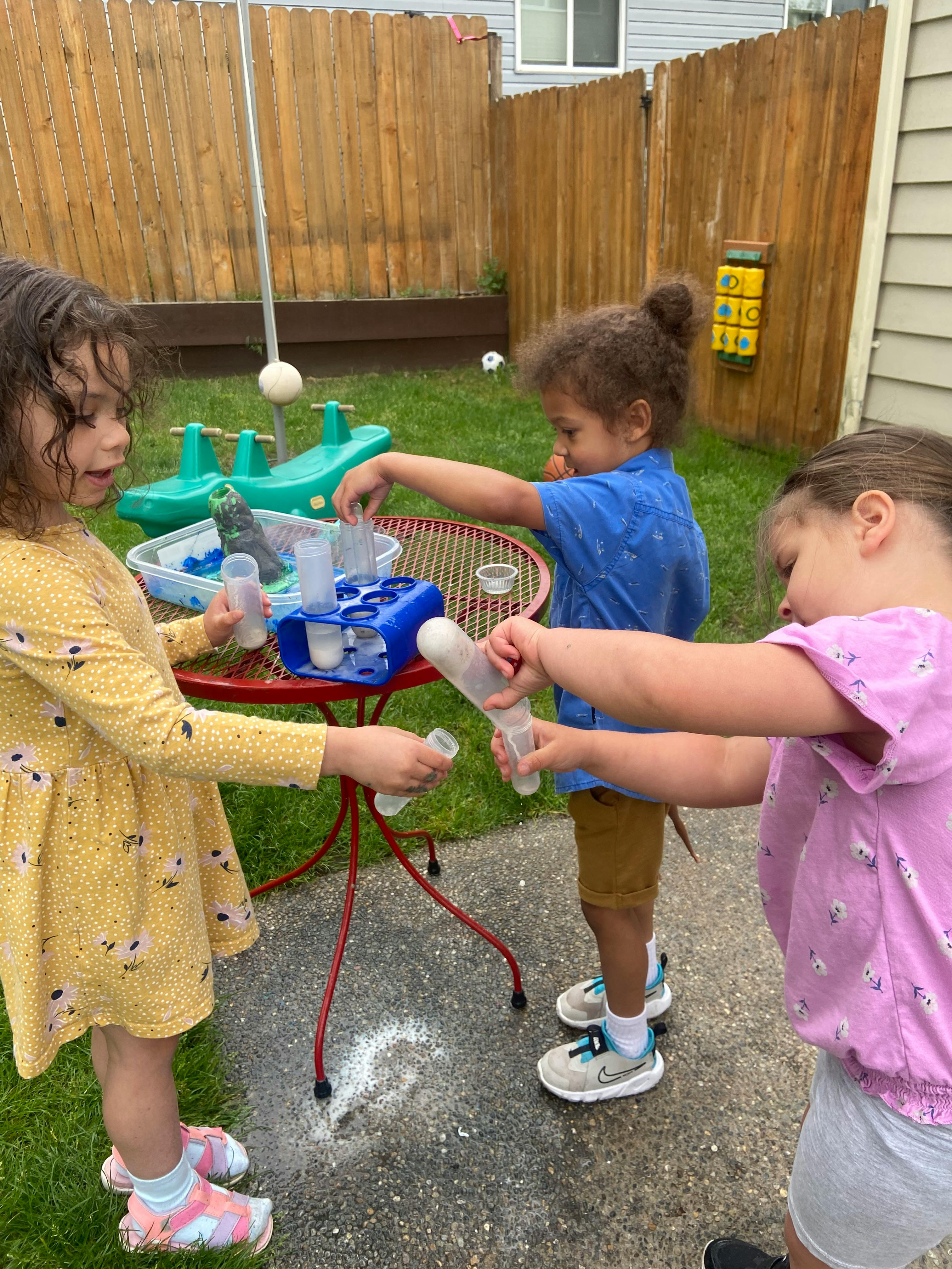 Three children playing with science experiment tools outdoors