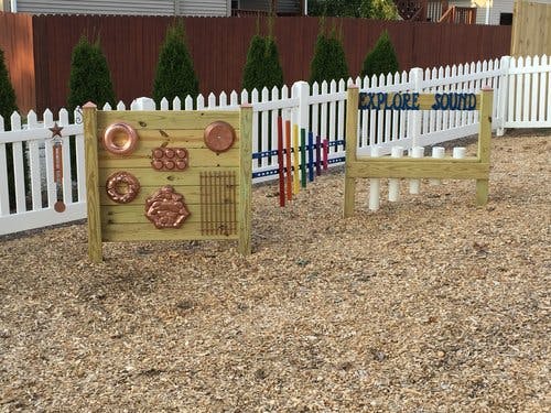 Outdoor sound exploration station with various instruments and "Explore Sound" sign