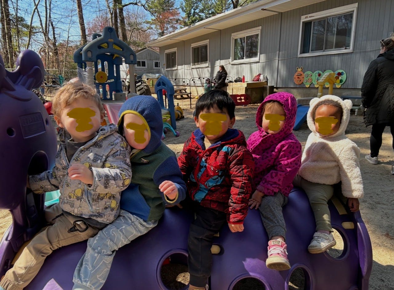 Five children sitting on purple playground equipment