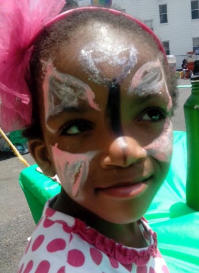 Child with face paint and a pink headband