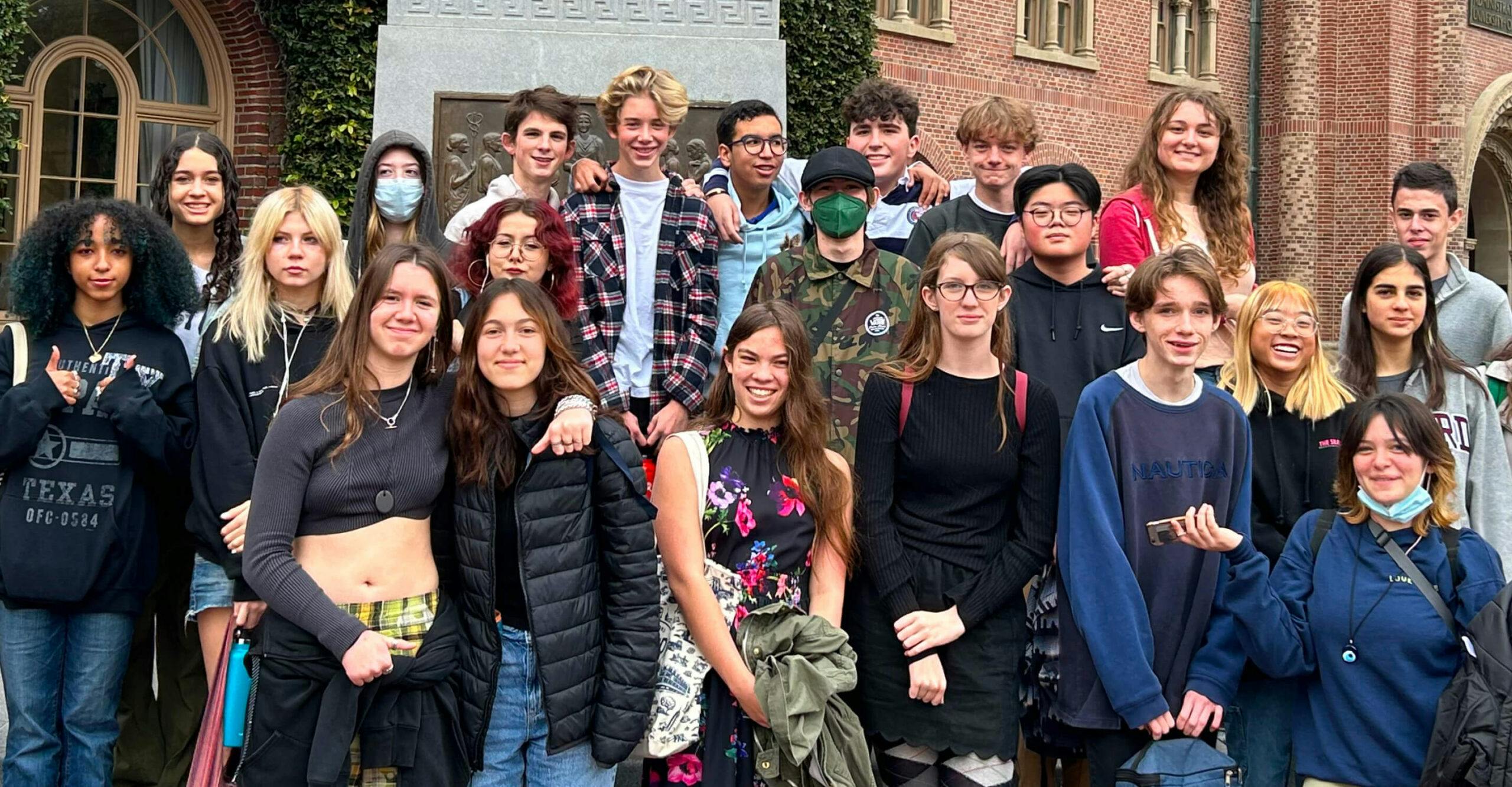 Group of teens posing outdoors with brick building in the background