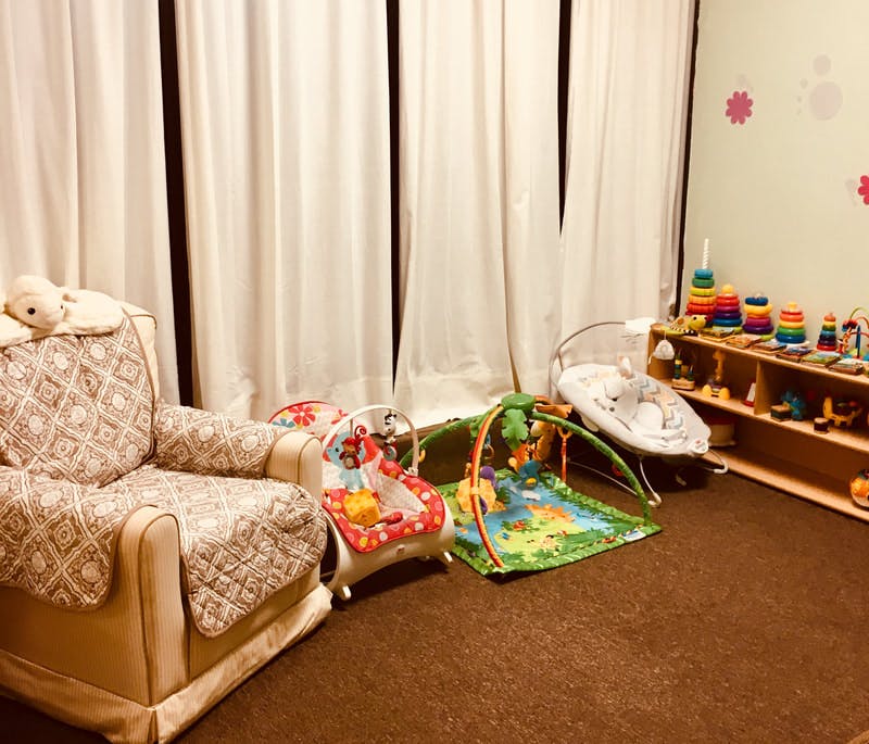 Nursery room with a chair, baby play mat, and toys on shelves